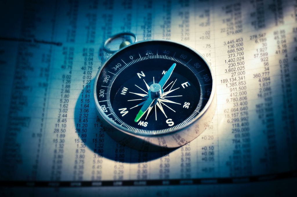 A compass lying on top of stock reports.
Image from Unsplash.